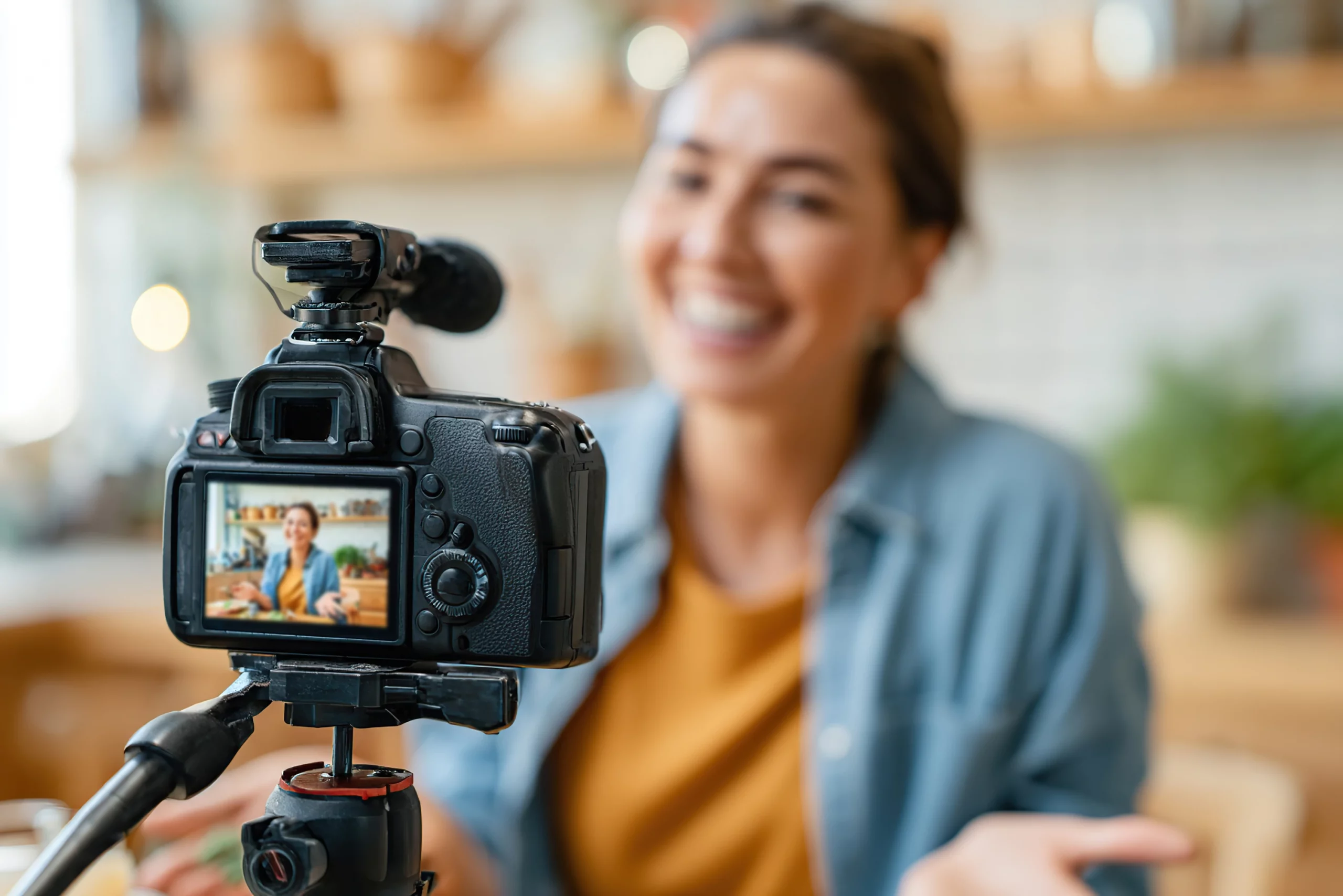 Videokamera auf Stativ filmt eine lächelnde Frau, die vor der Linse spricht; die Szene zeigt den Prozess einer professionellen Videoproduktion mit moderner Technik, kreativem Storytelling und hochwertigem Unternehmens- oder Social-Media-Content.