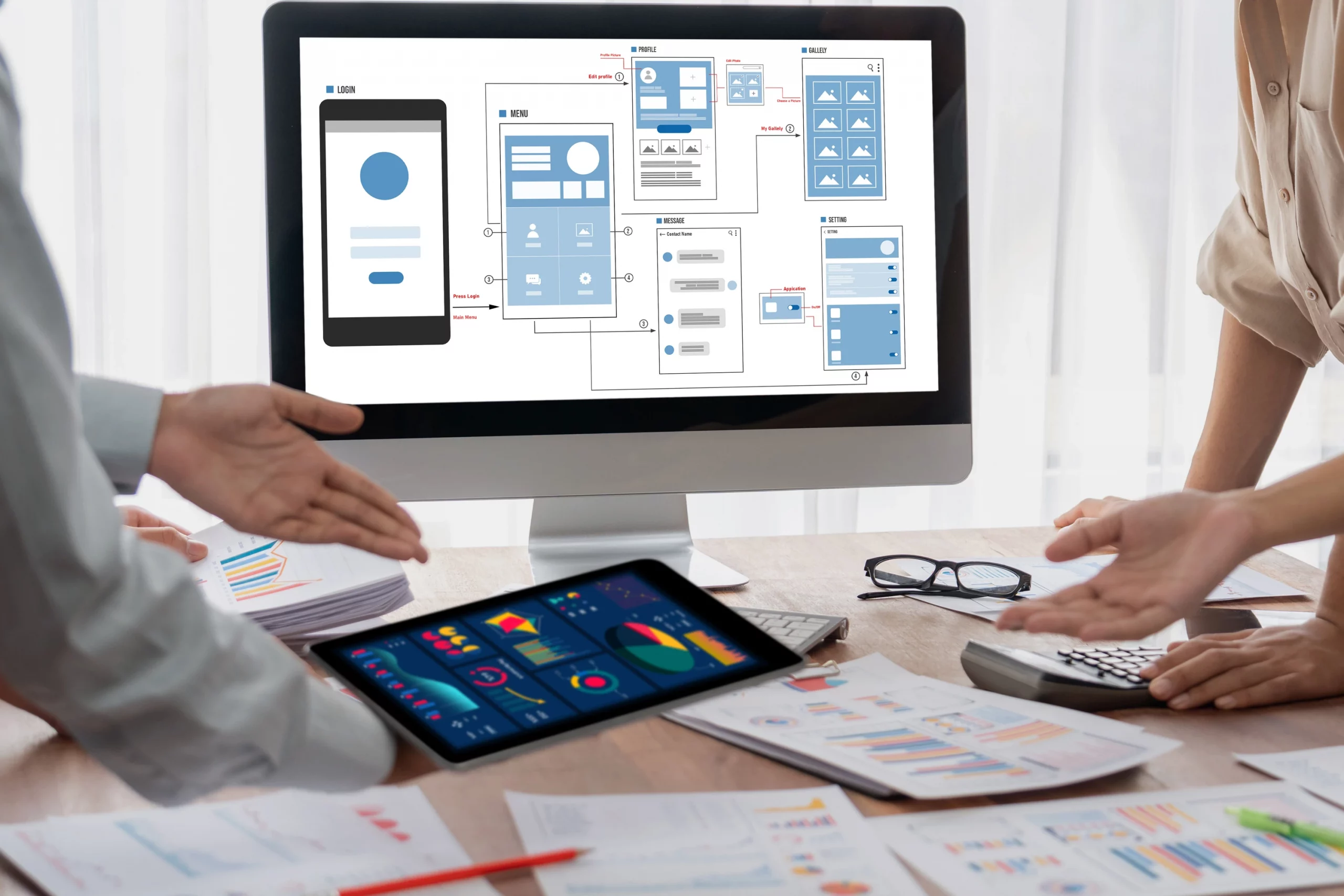 Person präsentiert digitale Layouts auf Monitor und Tablet; Arbeitsumgebung mit Grafiken und Diagrammen symbolisiert automatisiertes Database Publishing, bei dem Inhalte aus Datenbanken direkt in Druckvorlagen übertragen werden